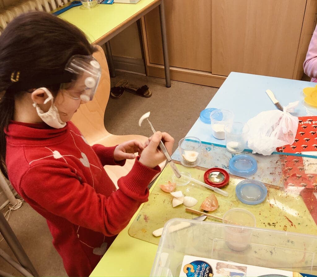 Ein Kind in der Grundschule, das im Freien Forschen herausfindet, warum Zwiebeln in den Augen brennen.