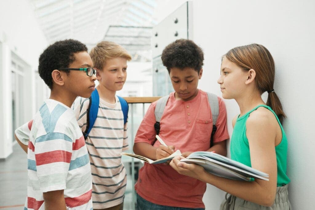 4 Schüler während einer Gruppenarbeit auf dem Flur des Schulgebäudes.