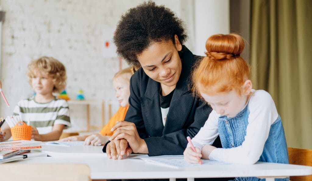 Eine Lehrerin begleitet eine Schülerin in der Grundschule beim Bearbeiten des Satzes der Woche im Deutsch-Unterricht.