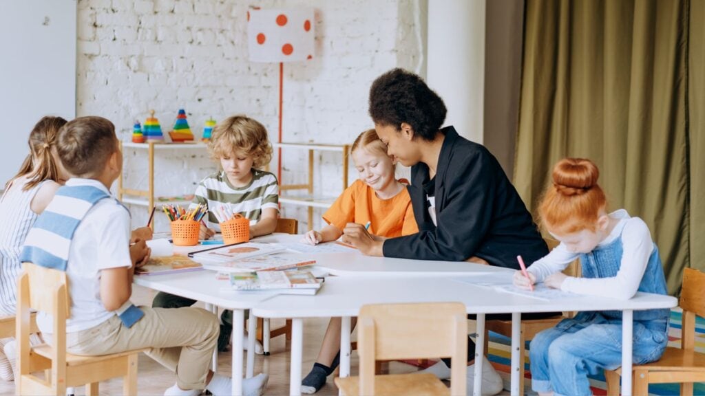 Eine Lehrerin, die sich im Klassenraum den individuellen Bedürfnissen ihrer Schüler annimmt und entsprechend ihrer Fähigkeiten differenziert.