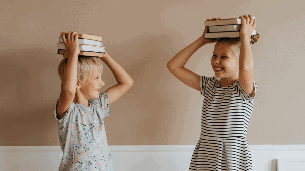 Klassenleitung Grundschule: Wie du eine starke Klassengemeinschaft aufbaust und dabei entspannt bleibst 8 2 Kinder mit einem Stapel Büchern auf dem Kopf