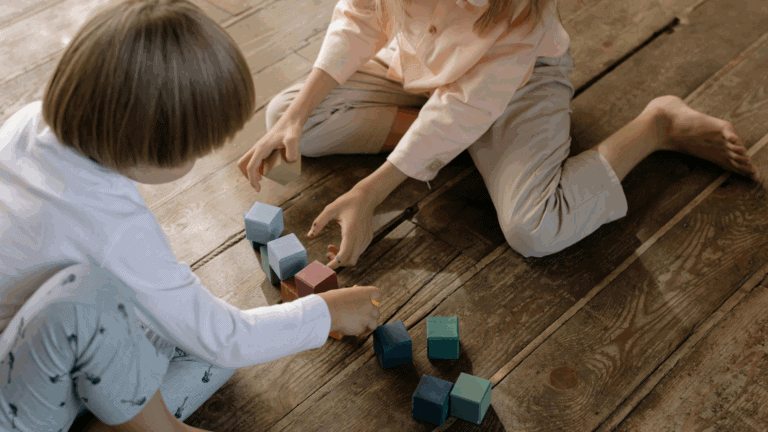 Zwei Kinder, die im Klassenraum auf dem Boden spielen.