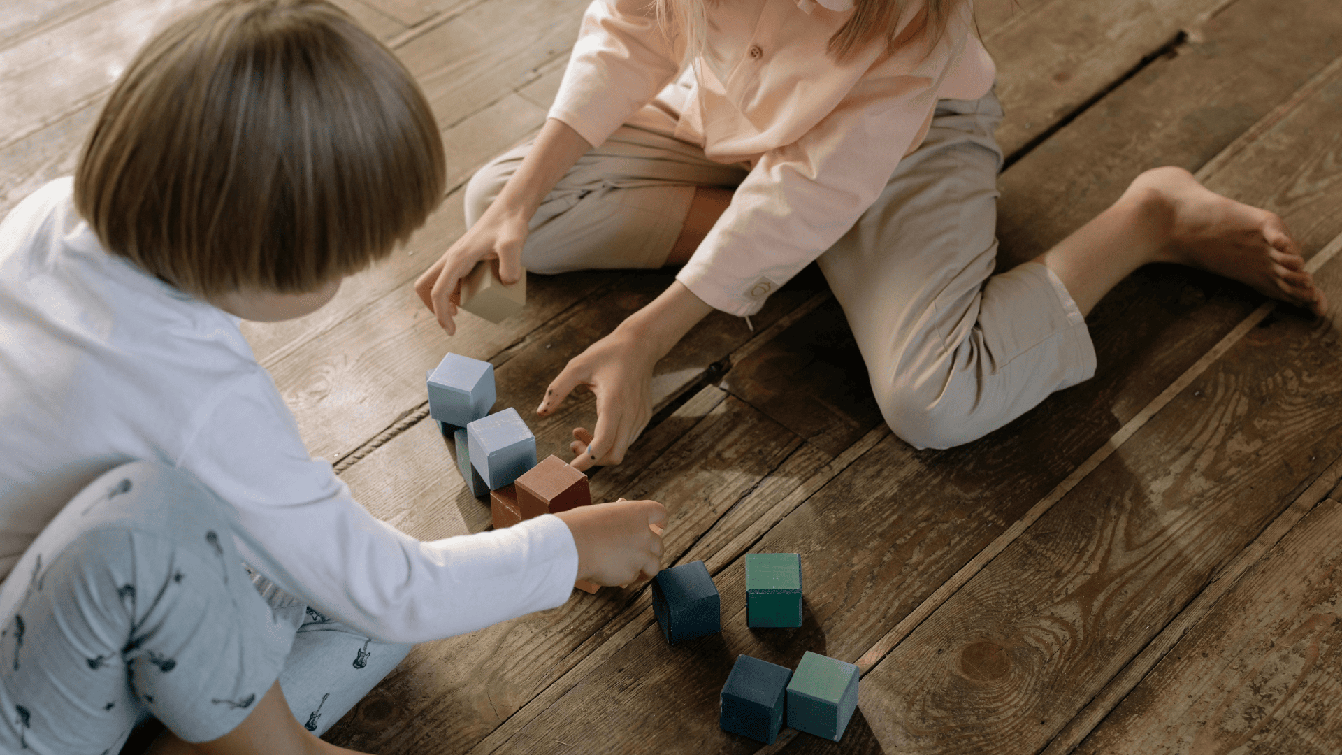 Zwei Kinder, die im Klassenraum auf dem Boden spielen.