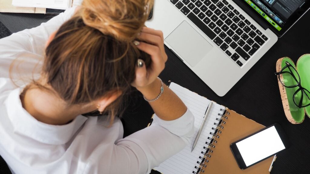 Eine Lehrerin, die am Schreibtisch am Computer verzweifelt